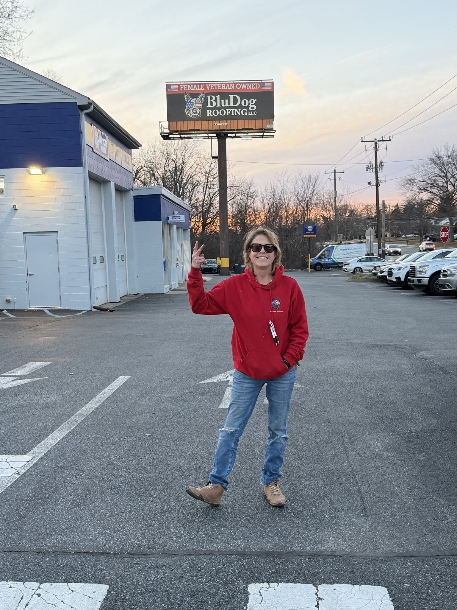 BluDog Roofing owner Kimberley Sammon standing below the BluDog billboard