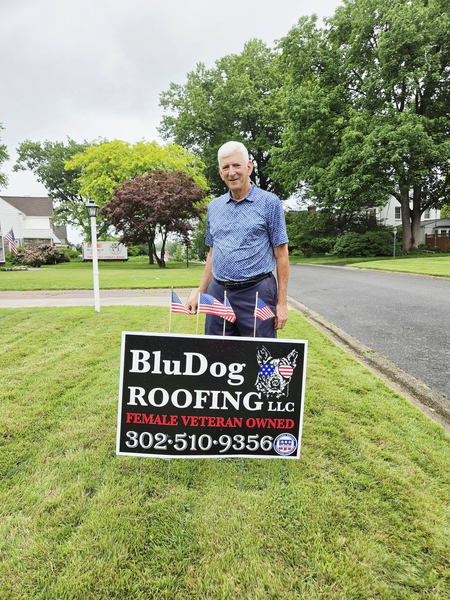 Homeowner beside a BluDog Roofing yard sign